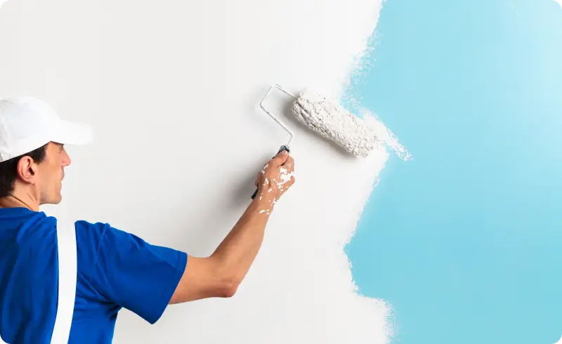 Painter using roller, painting wall blue.