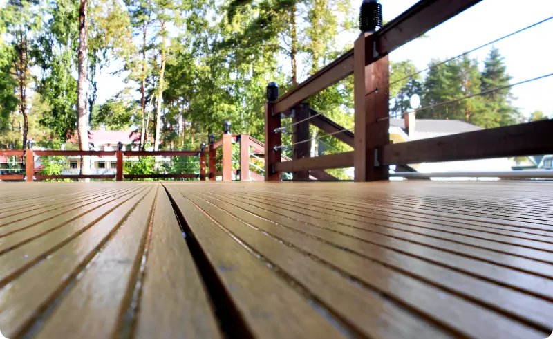 Wooden deck overlooking trees and houses.