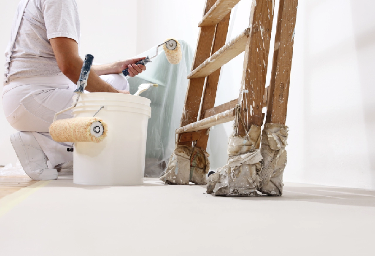 Painter using roller and paint tray.