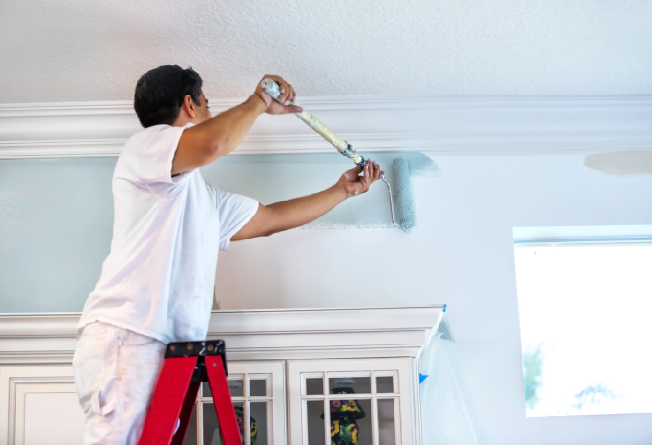 Painter using roller to paint crown molding.