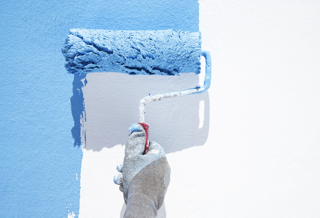 Hand painting wall with blue paint roller.